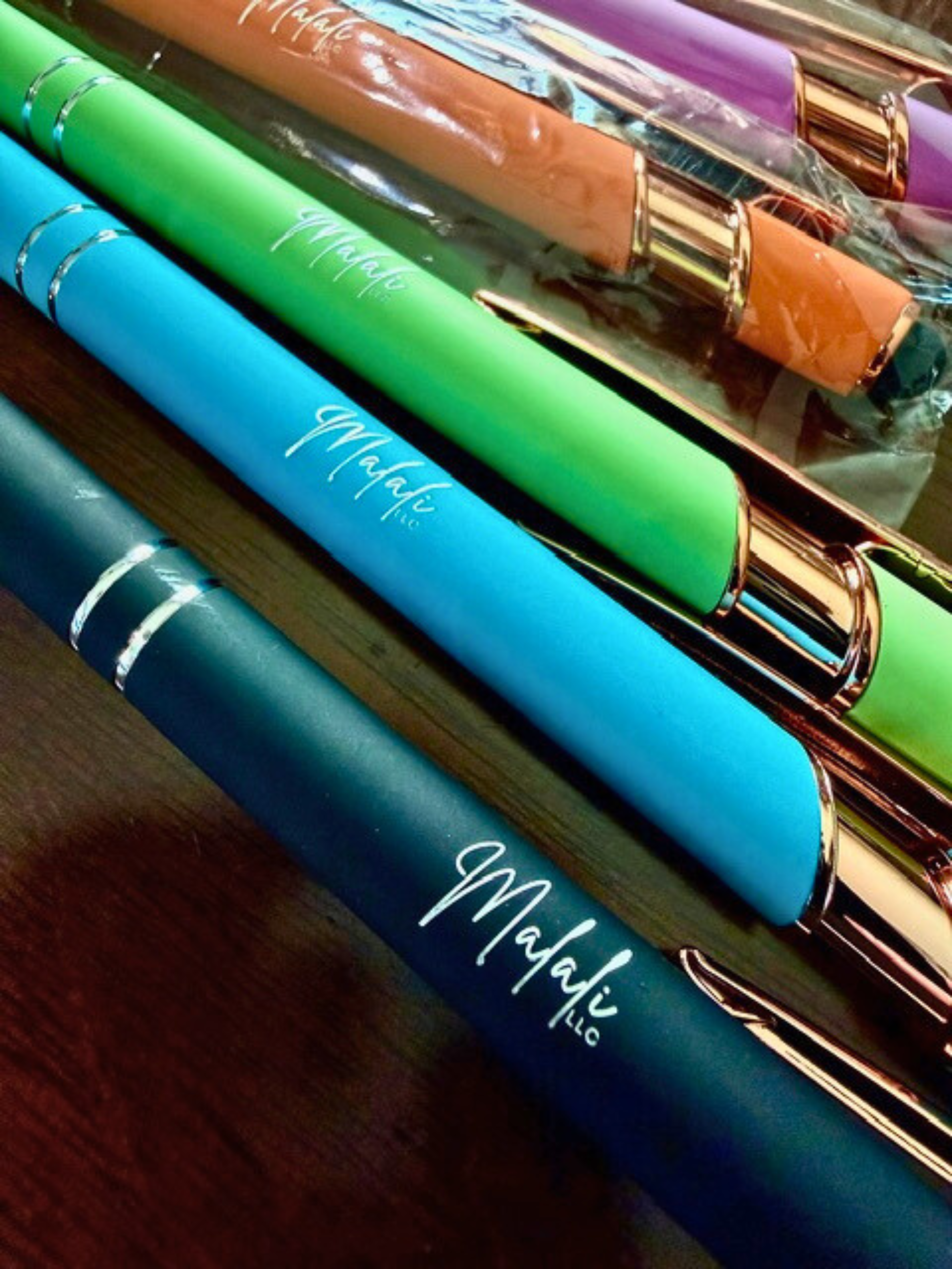 Colorful pens with gold accents on a reflective surface